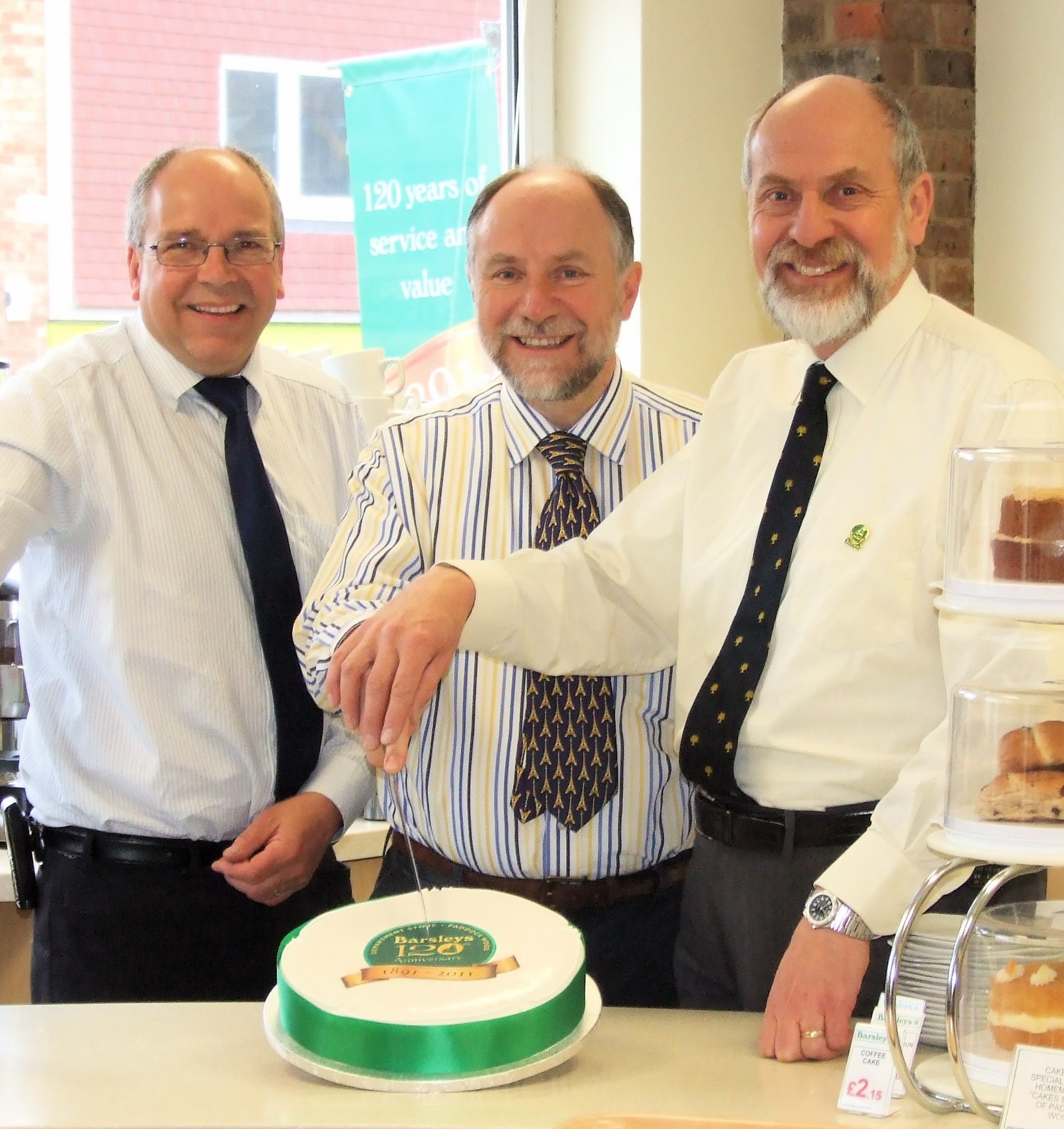 Barsleys family members cutting a cake to celebrate 120 years in 2011